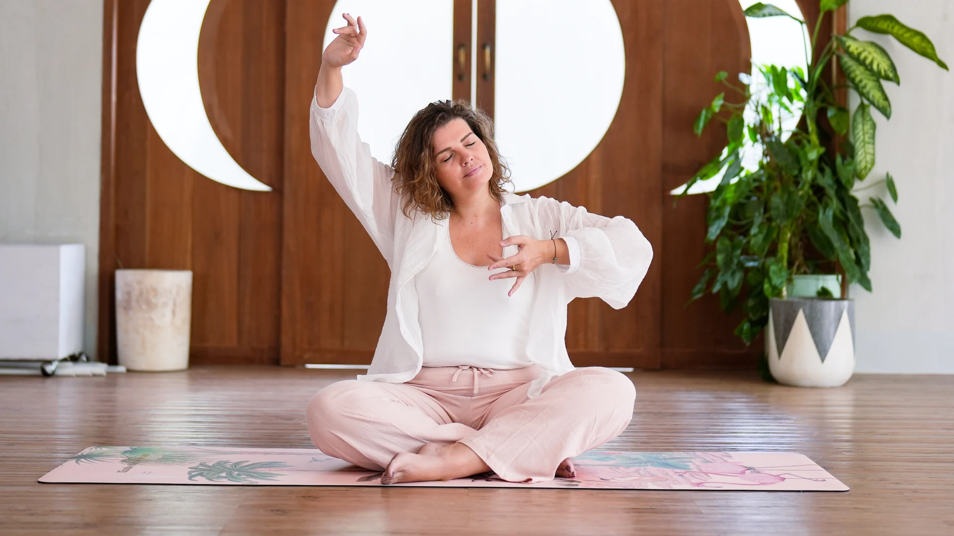 Julie pratique le Breathwork, assise devant la porte lunaire, un bras levé